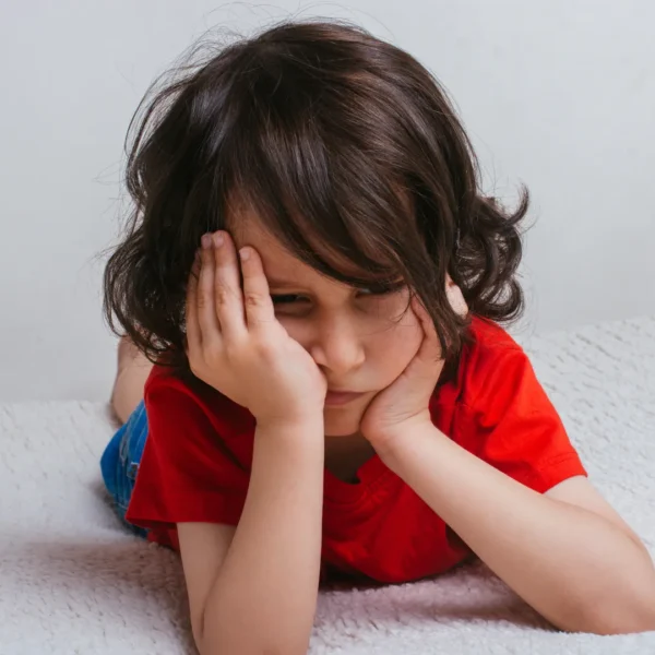 Young child lying on the floor looking disappointed, illustrating how to help your child handle disappointment