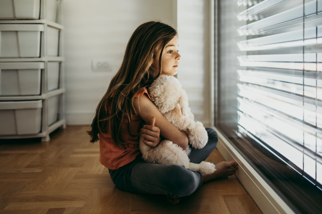 Young girl showing signs of social anxiety, looking withdrawn and uncertain