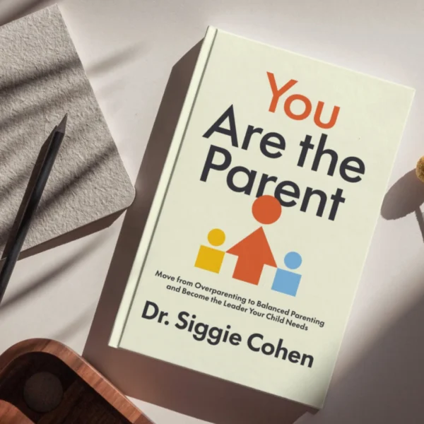 You Are The Parent by Dr. Siggie Cohen, laid flat on a bright surface alongside a notebook and pencil
