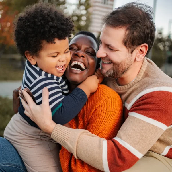 Happy child laughing with parents outdoors, illustrating the joy of confident parenting with clear boundaries and age-appropriate choices