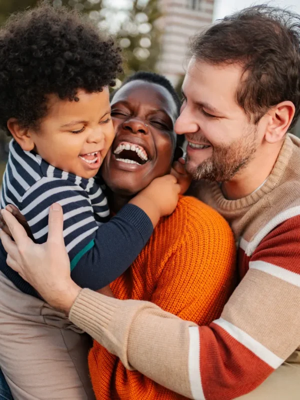 Happy child laughing with parents outdoors, illustrating the joy of confident parenting with clear boundaries and age-appropriate choices